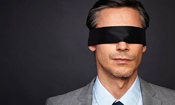 Closeup of man in suit and tie wearing blindfold