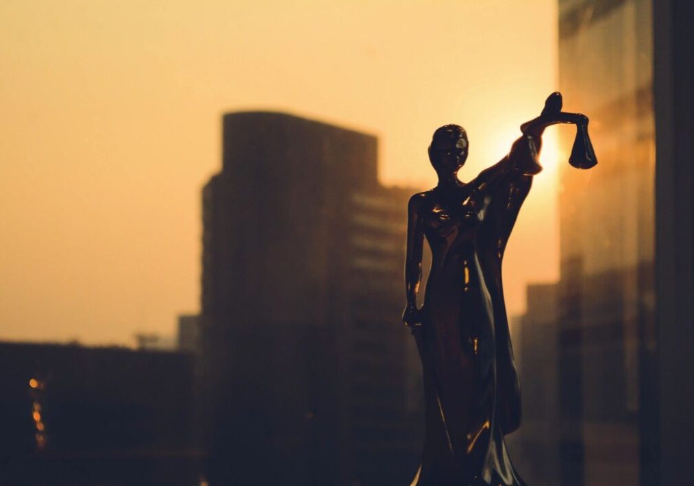 A statue of a judge in front of a city