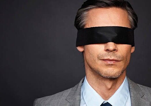 Closeup of man in suit and tie wearing blindfold